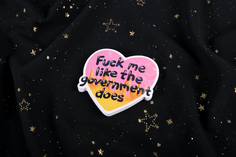 A flaming heart-shaped sticker with the text "Fuck me like the government does"