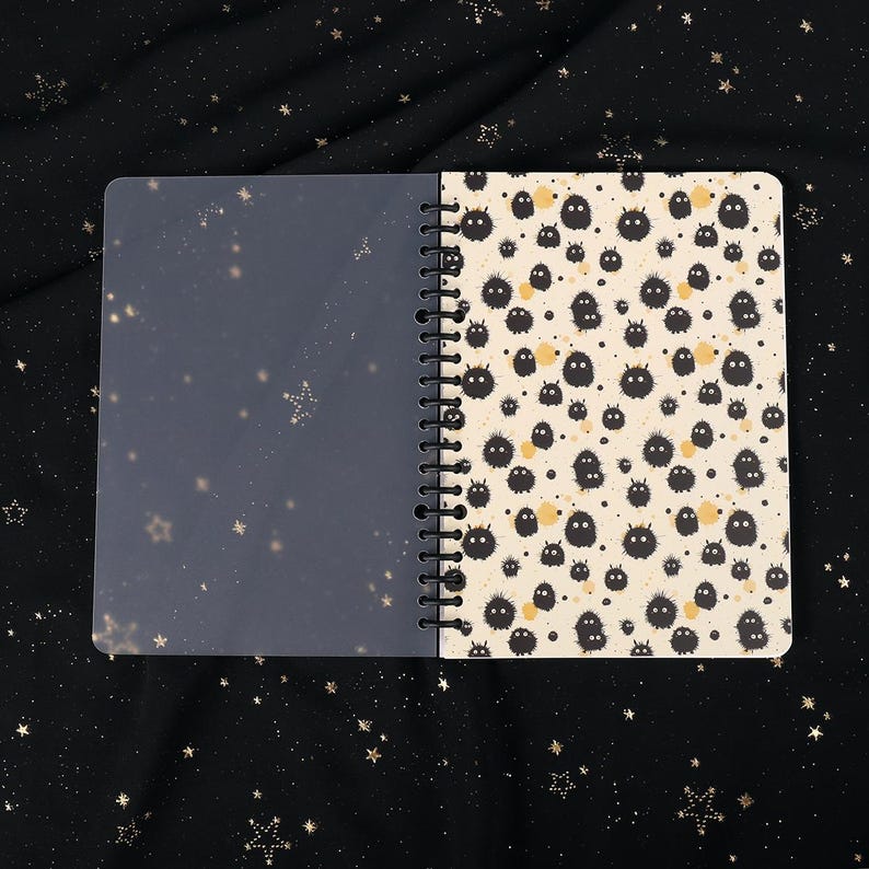 Puede incluir: Un cuaderno de espiral con una cubierta de pl&aacute;stico transparente y una cubierta blanca con un patr&oacute;n repetitivo negro y amarillo de peque&ntilde;as criaturas peludas.