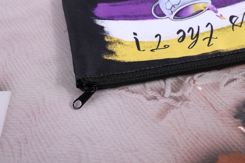 Puede incluir: Bolsa negra con cremallera con un dise&ntilde;o colorido que presenta una taza de t&eacute; y el texto "i love the tea!". El dise&ntilde;o incluye colores morado, blanco y amarillo. La bolsa tiene una cremallera negra y un tirador negro.
