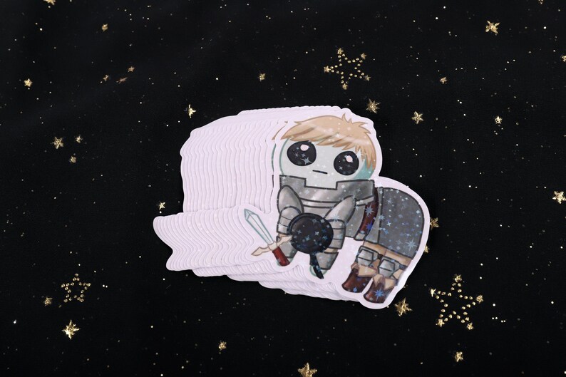 A holographic sticker Of Laios Touden  of Dungeon Meshi / Delicious in dungeon imagined as the yippee / Autism Creature. The sticker is on a black background with gold glitter.
