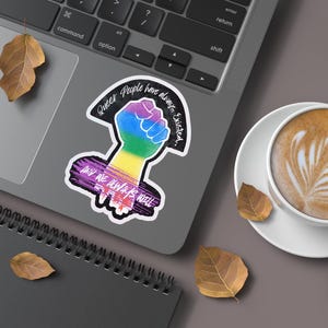 Queer People have always existed, and always will, Broken Glass Style Holographic 3 inch sticker, rainbow colored power fist mockup, On a Laptop
