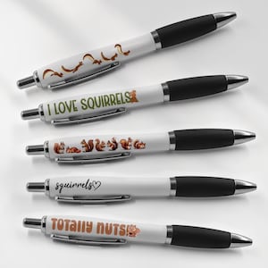 May include: Five white pens with black caps and different squirrel-themed designs. The designs include squirrels running, the text "I love squirrels", squirrels sitting, the text "squirrels", and the text "Totally Nuts".