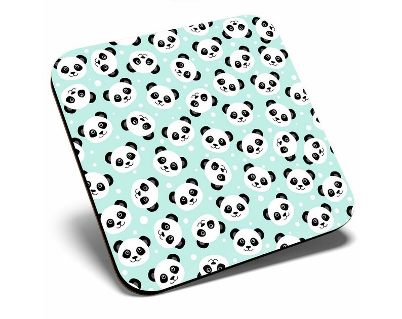 May include: A square coaster with a light blue background and a repeating pattern of black and white panda faces. The panda faces are cartoon-like and have a simple design.