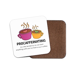 May include: White square coaster with the word "PROCAFFEINATING" and a definition. The coaster features two coffee cups, one pink and one yellow, with heart-shaped latte art. A brown cork coaster is next to it.