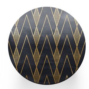 May include: Circular, dark grey surface with a gold geometric design. The pattern consists of gold chevrons and horizontal lines. The surface has a textured look and is set against a white background.