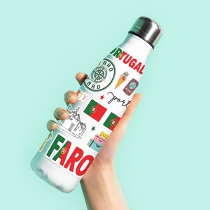 Op de afbeelding: Een witte herbruikbare waterfles met verschillende kleurrijke stickers, waaronder een kompas, een Portugese vlag en de woorden "Portugal" en "Faro".