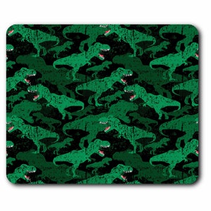 May include: A rectangular mouse mat with a repeating pattern of green Tyrannosaurus Rex dinosaurs on a camouflage background. The dinosaurs have open mouths with red tongues and white teeth. The background is a mix of black and dark green.