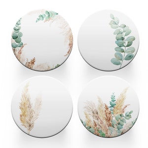 May include: Set of four round coasters featuring a white background with watercolour illustrations of pampas grass and eucalyptus leaves.