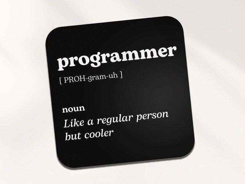 Op de afbeelding: Zwarte en witte onderzetter met het woord "programmeur" in vetgedrukte witte letters en een definitie van het woord eronder. De definitie luidt: "[PROH-gram-uh] zelfstandig naamwoord Net als een gewoon persoon, maar cooler."