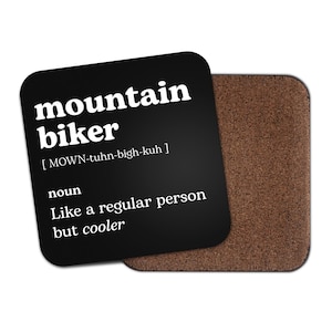 May include: Black coaster with white text that reads "mountain biker [MOWN-tuhn-bigh-kuh] noun Like a regular person but cooler"