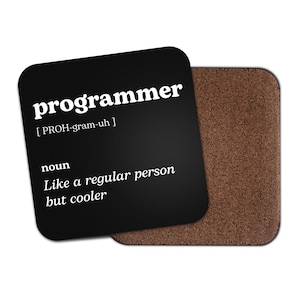 May include: Black coaster with white text that reads "programmer [PROH-gram-uh] noun Like a regular person but cooler".