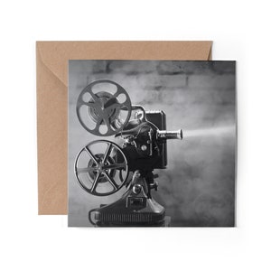 May include: A vintage black and white film projector with a large lens and two spools of film. The projector is emitting a plume of smoke, suggesting it is in operation.