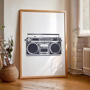 Może przedstawiać: Czarno-biały nadruk przedstawiający zabytkowy boombox w drewnianej ramie. Grafika przedstawia szczegółową ilustrację systemu stereo, w tym głośniki, pokrętła i odtwarzacz kaset. Nadruk jest wyświetlany na białym tle.