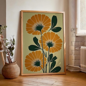 Puede incluir: Una impresión artística enmarcada con flores naranjas estilizadas con centros y hojas de color verde oscuro sobre un fondo verde claro. La obra de arte está en un marco de madera y se apoya contra una pared. El tema general es botánico.