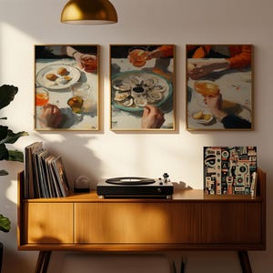 Pu&ograve; includere: Tre stampe artistiche incorniciate raffiguranti una scena di ristorazione con cibo e bevande. Le stampe sono appese sopra un mobile in legno con un giradischi e dischi in vinile. Una grande pianta verde &egrave; nell'angolo.