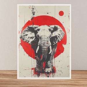 Può includere: Stampa artistica di un elefante in bianco e nero, con un cerchio rosso sullo sfondo. Lo sfondo è bianco sporco con schizzi di vernice rossa, creando un contrasto sorprendente. L'opera è incorniciata e su una superficie di legno.