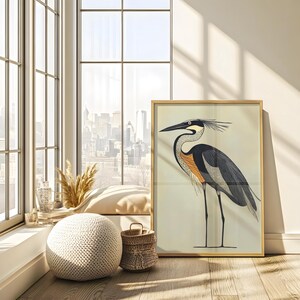Puede incluir: Una impresi&oacute;n enmarcada de una ilustraci&oacute;n estilizada de una garza con plumas negras, grises, naranjas y blancas. La garza est&aacute; de pie sobre un fondo beige claro.