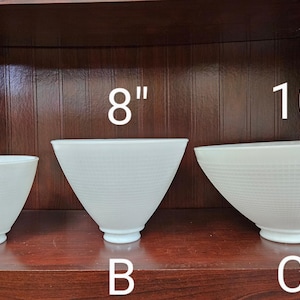 May include: Three white frosted glass lampshades of different sizes, labeled 6", 8", and 10". The lampshades are sitting on a wooden shelf.