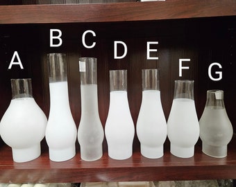 May include: Eight frosted glass lampshades of varying sizes and shapes, labeled A through G. The lampshades are arranged in a row on a wooden shelf.