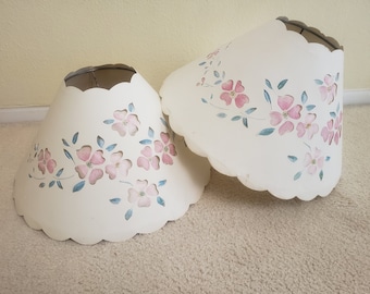 May include: Two white lampshades with scalloped edges and pink floral designs. The lampshades have a delicate, feminine aesthetic.