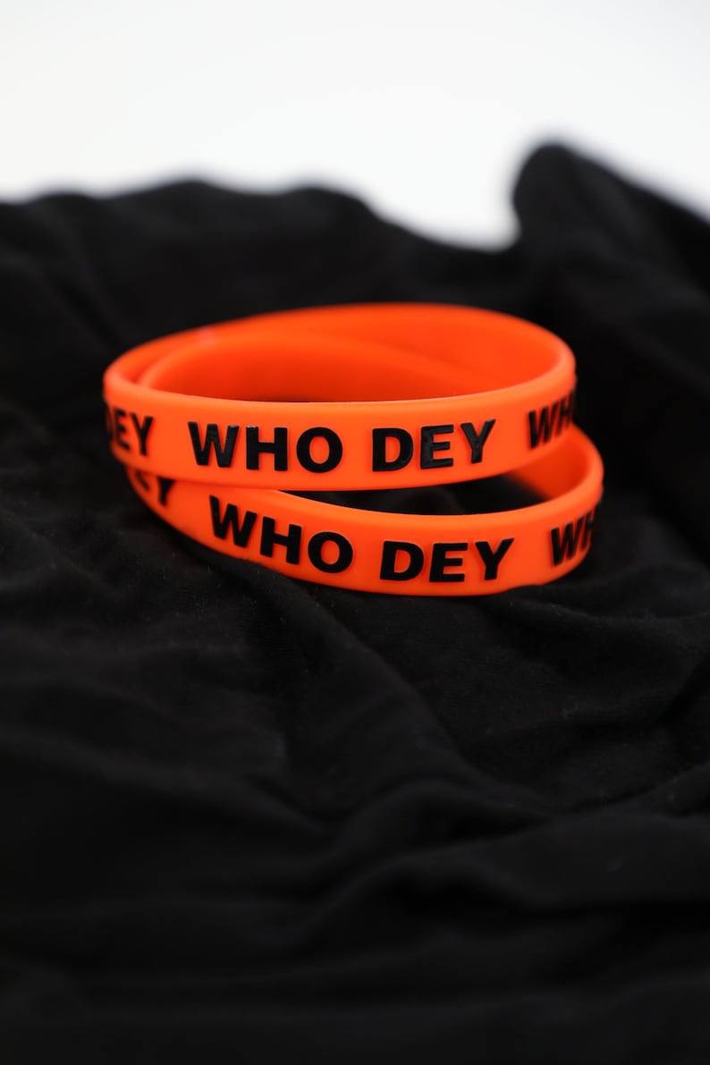 May include: Two orange silicone wristbands with the text "WHO DEY" printed in black.