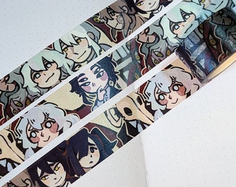 May include: Four rolls of decorative washi tape with repeating anime-style character illustrations. The characters have various hair colors and expressions, set against a beige and burgundy background. The tape is angled across a white dotted notebook page.