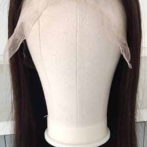May include: A dark brown human hair wig on a mannequin head with a lace front. The wig is straight and has a blunt cut.