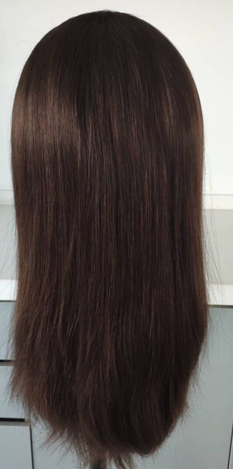 May include: A long, straight, dark brown wig on a mannequin head.