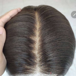 May include: Close-up of a dark brown human hair wig with a lace front. The hair is parted in the middle and styled in a straight, sleek look.