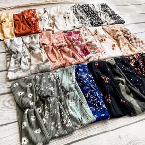 May include: A collection of 18 colorful and patterned headbands. The headbands are made of a soft, stretchy fabric and have a knotted design. The headbands are in a variety of colors and patterns, including floral, striped, and geometric.