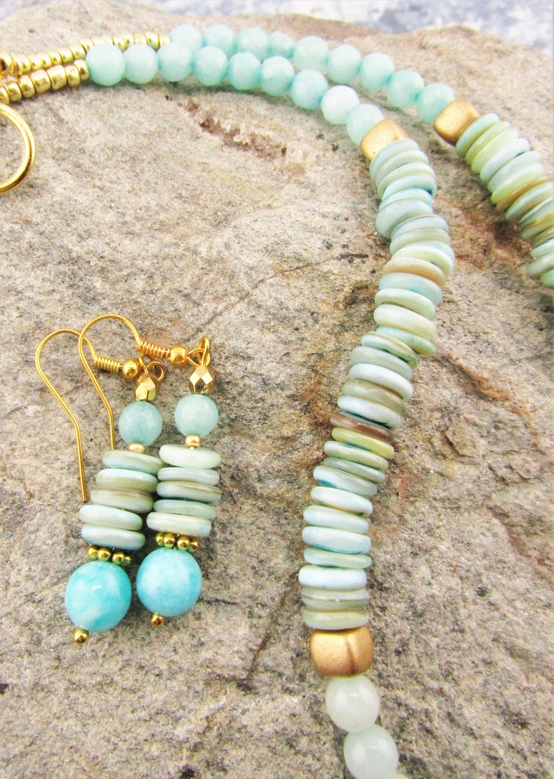 May include: A turquoise and gold necklace and earrings set. The necklace is made with turquoise beads and gold spacers. The earrings are made with turquoise beads and gold hooks.