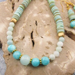 May include: A turquoise and gold necklace and earrings set. The necklace features round turquoise beads and gold spacers. The earrings are drop earrings with turquoise beads and gold accents.