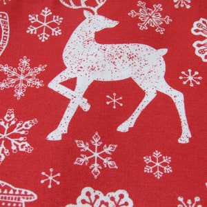 May include: Red fabric with a repeating pattern of white reindeer and snowflakes. The reindeer are stylized with antlers and the snowflakes vary in design. The overall theme is festive and seasonal, suitable for holiday decorations.