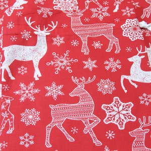 May include: Red fabric with a repeating pattern of white reindeer and snowflakes. The reindeer have detailed patterned bodies and antlers. The snowflakes vary in size and design, creating a festive holiday theme.