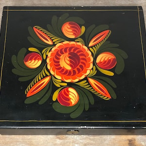 May include: A black wooden box with a hinged lid. The lid is decorated with a hand-painted floral design in shades of red, orange, yellow, and green.