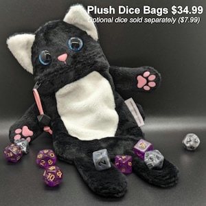 Puede incluir: Una bolsa de dados de felpa negra con forma de gato con detalles blancos, almohadillas rosas y ojos azules. La bolsa tiene un cierre de cremallera y un tirador rosa. Varios dados de m&uacute;ltiples caras de varios colores est&aacute;n esparcidos alrededor de la bolsa. El texto de la imagen dice "Plush Dice Bags".