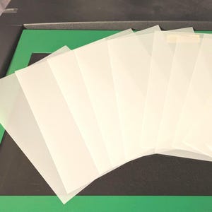 May include: A stack of six translucent white sheets of paper.