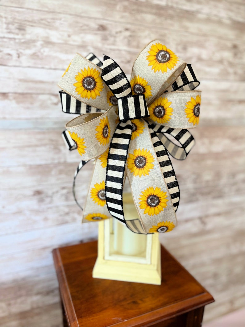 Puede incluir: Un gran lazo de rayas blancas y negras con girasoles, perfecto para a&ntilde;adir un toque de encanto r&uacute;stico a la decoraci&oacute;n de tu hogar.