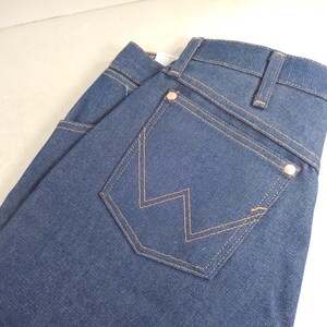 May include: A pair of dark blue denim jeans with a back pocket featuring a distinctive W-shaped stitching.