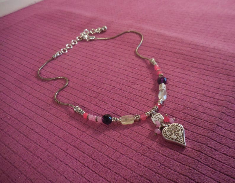 May include: Silver-toned necklace with a heart pendant and colorful beads. The pendant has an ornate design and the necklace features pink, purple, and clear beads. The text "Listen to your heart" is on a small charm.