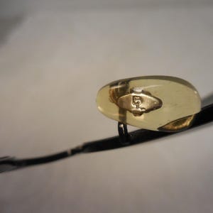 May include: Close-up of eyeglasses with a black frame and gold-colored nose pads. The nose pads have a gold-colored emblem. The lenses are not visible in the image.