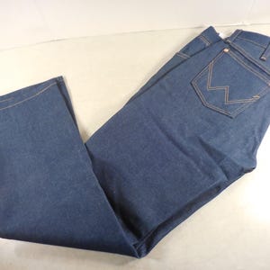 May include: A pair of dark blue denim jeans with a single back pocket featuring a stitched 'W' logo.