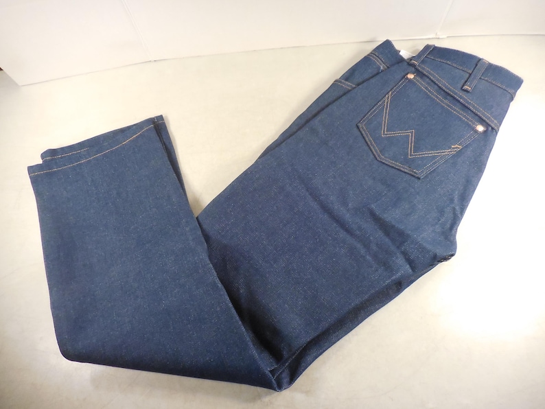 May include: A pair of dark blue denim jeans with a single back pocket featuring a stitched 'W' logo.