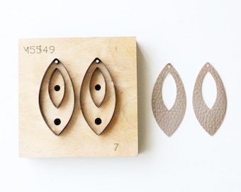 May include: A close-up of a leather craft die set with two die cuts of a leaf shape with a hole in the middle. The die set is made of wood and has the number "7" printed on it. The die set is labeled "M5549". Two leather leaf shapes are shown cut out with the die set.