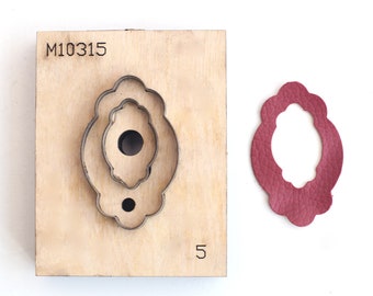 May include: A wooden die-cut tool with a metal frame in an oval shape, next to a cut-out piece of burgundy leather. The tool has the number "5" and the text "M10315" engraved on it.
