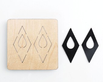 May include: A wooden die-cutting template with two diamond-shaped cutouts, and two black leather earrings with a teardrop-shaped cutout.