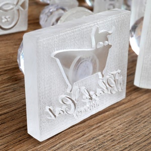 May include: A clear plastic stamp with a white silhouette of a cow and the text "Cow & Calf" in a cursive font.