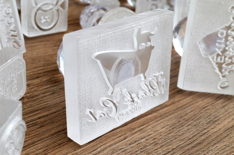 May include: A clear plastic stamp with a white silhouette of a cow and the text "Cow & Calf" in a cursive font.