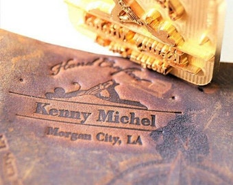 Może przedstawiać: Zbliżenie na skórzaną pieczęć z wytłoczonym tekstem "Handcrafted by Kenny Michel Morgan City, LA". Pieczęć wykonana jest z mosiądzu i ma szczegółowy wzór samolotu.