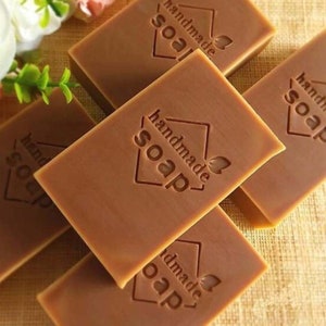 May include: Five bars of brown handmade soap with the words "handmade soap" embossed on each bar.